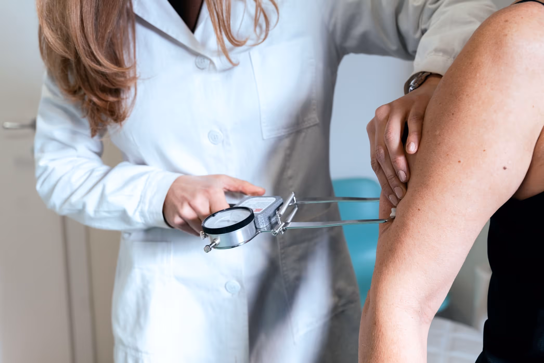 Nutrizionista misura la massa grassa del braccio di un paziente con un plicometro