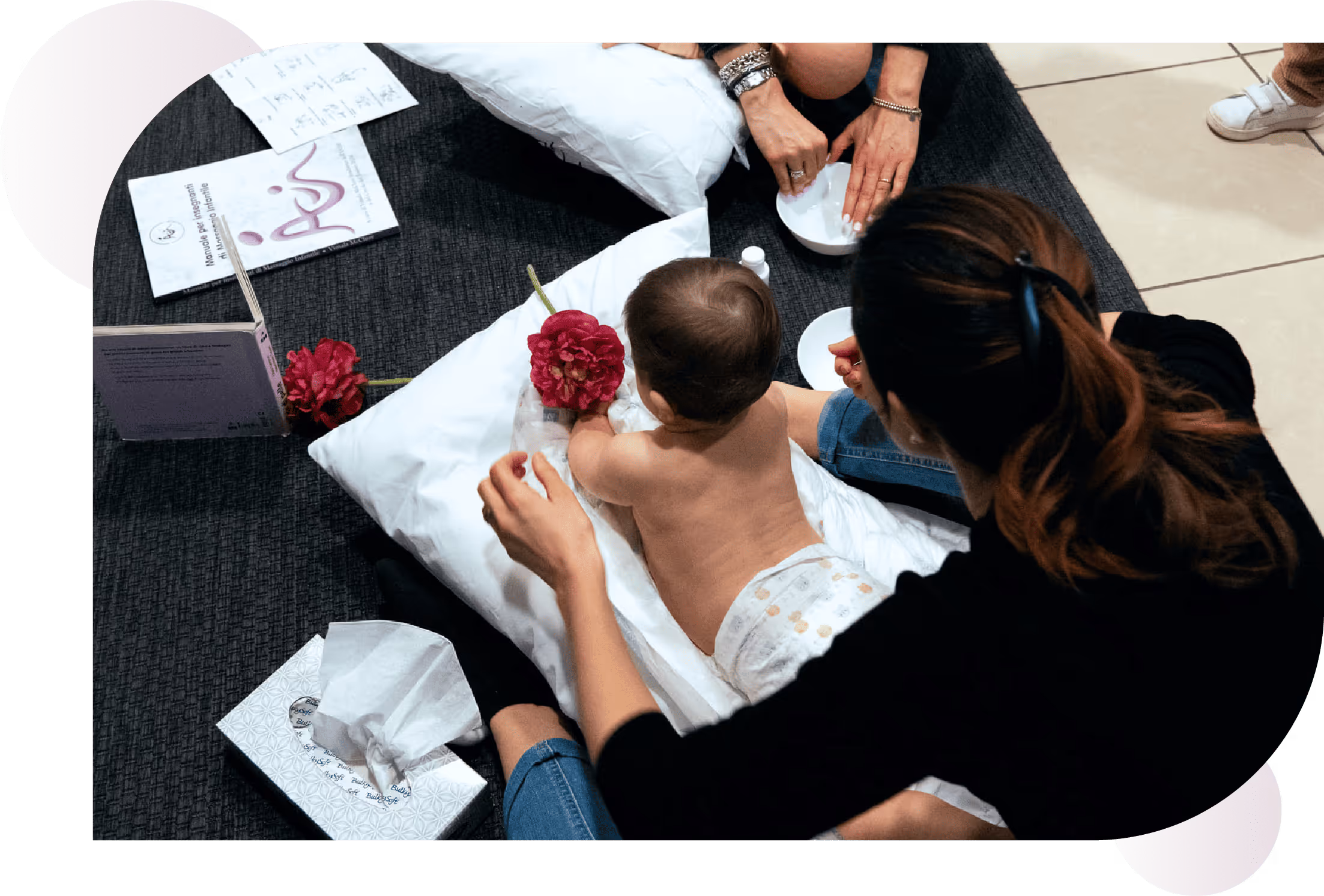 Mamma seduta a terra durante un corso con il suo bambino